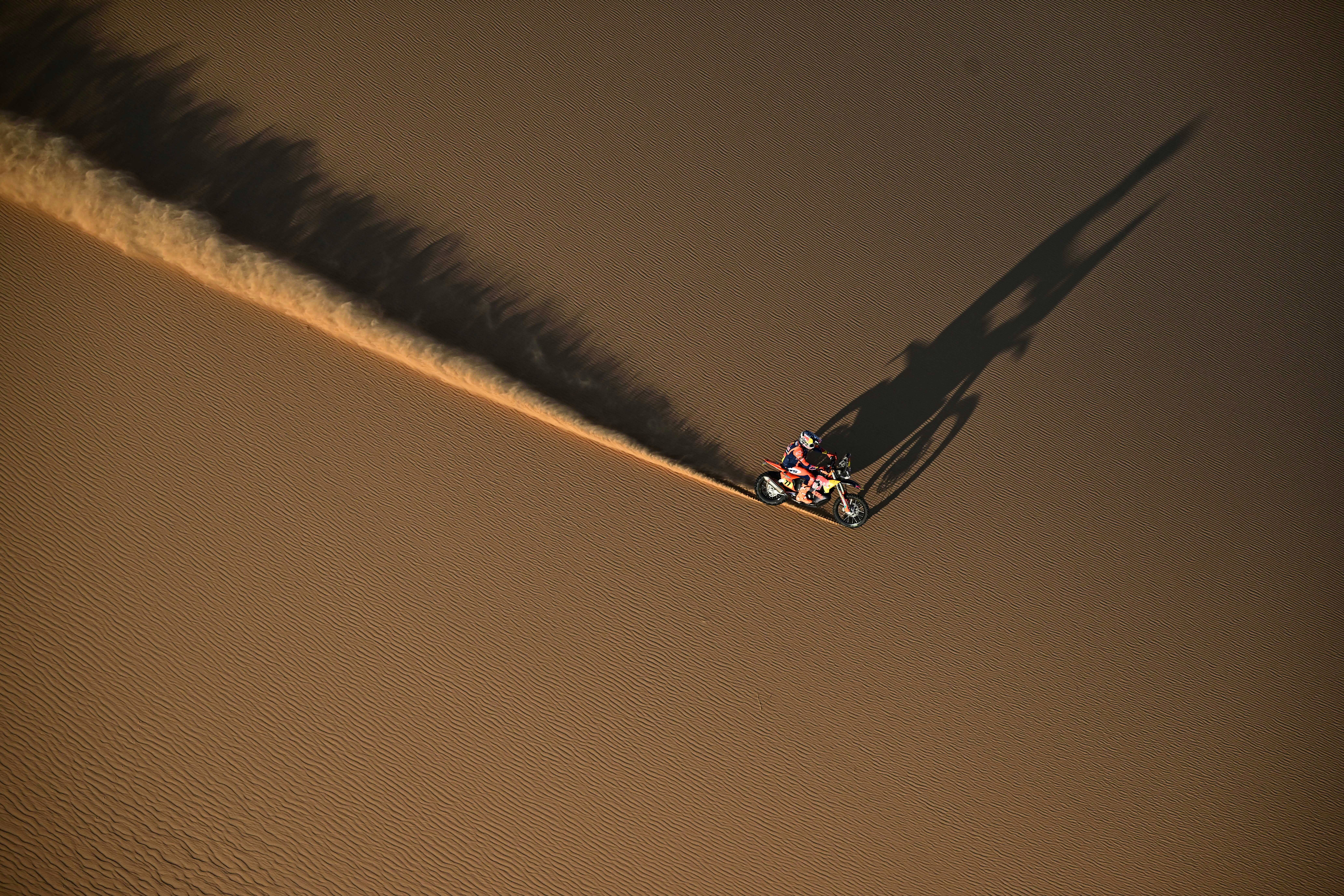 An aerial view of a motorcycle racer riding on a sand dune.