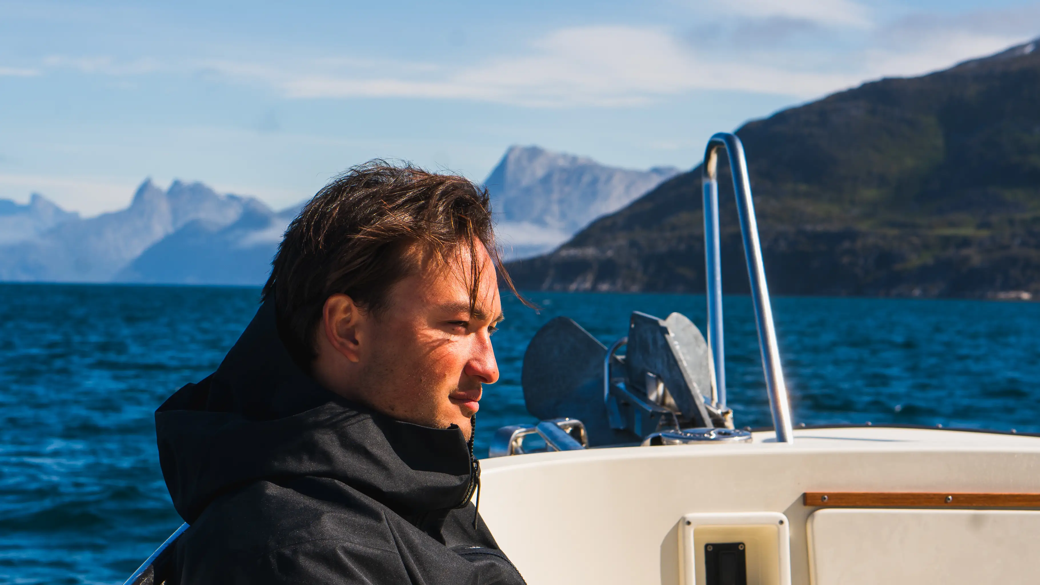 Casper Frank Møller on a boat with mountains in the background.