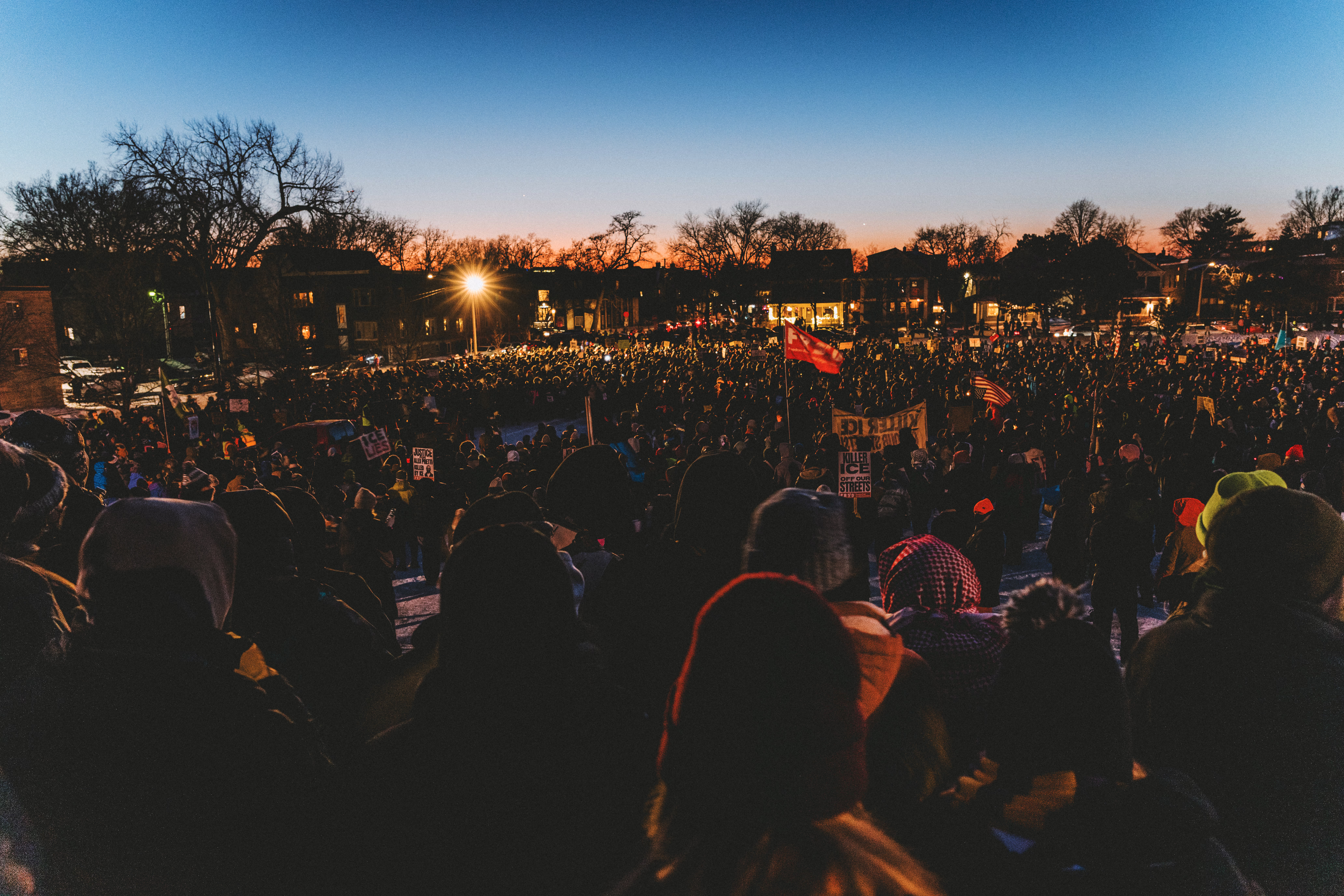 A large group of mourners are seen in the evening light at a vigil