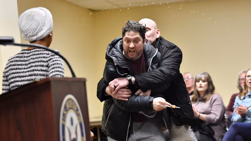 A man is tackled after spraying an unknown substance at US Representative Ilhan Omar (D-MN) (L) during a town hall she was hosting in Minneapolis, Minnesota, on January 27, 2026. (Photo by Octavio JONES / AFP via Getty Images)