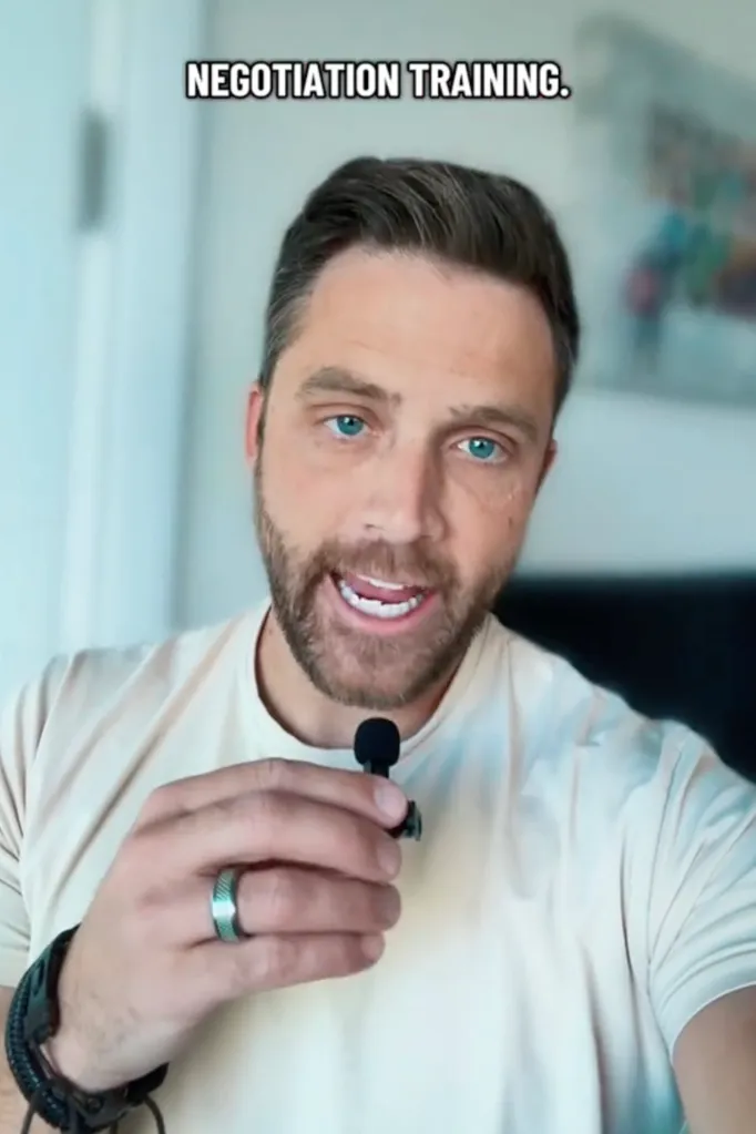 A man with a beard and a microphone talking about negotiation training.