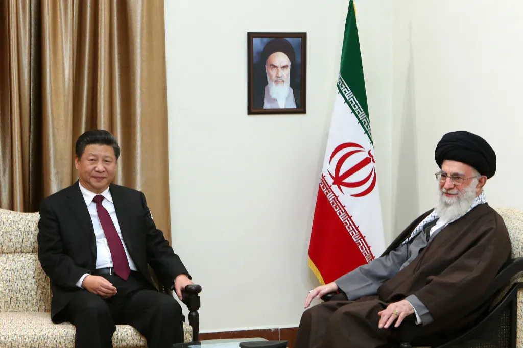Chinese President Xi Jinping and Iranian Supreme Leader Ayatollah Ali Khamenei sitting in chairs, with the Iranian flag and a portrait of Ayatollah Khomeini in the background.