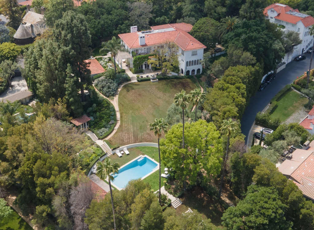 Aerial view of Angelina Jolie's Hollywood estate with a large white mansion, extensive gardens, and a swimming pool.