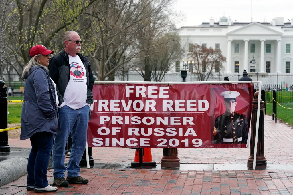 Joey and Paula Reed stand in Lafayette Park next to a banner reading 