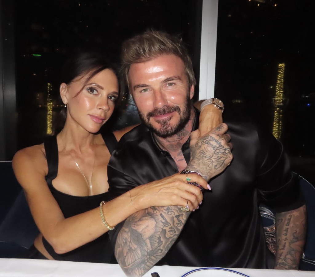 David and Victoria Beckham smiling at a dinner table.
