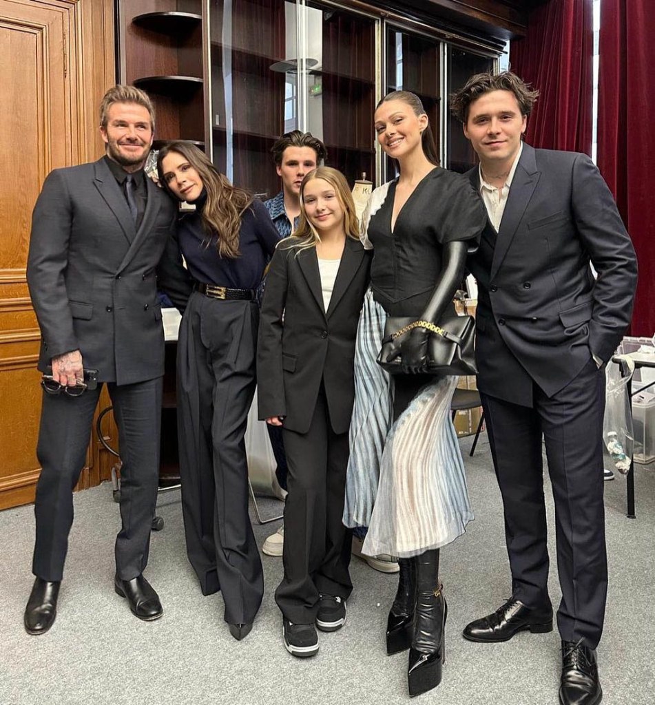 From left: David Beckham, in a black suit, shirt and tie, Victoria Beckham, in a black sweater and black pants, Cruz Beckham, in a blue shirt, Harper Beckham, in a black pant suit and white top, Nicola Peltz, in a black top and striped skirt, Brooklyn Beckham, in a black suit and white shirt, attend Victoria Beckham's Womenswear Fall Winter 2023-2024 show.