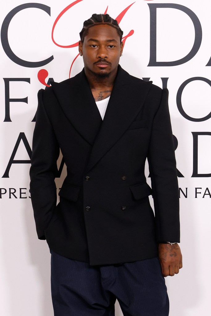 Stefon Diggs attends the CFDA Awards in a black double-breasted blazer, white shirt, and pinstriped trousers.