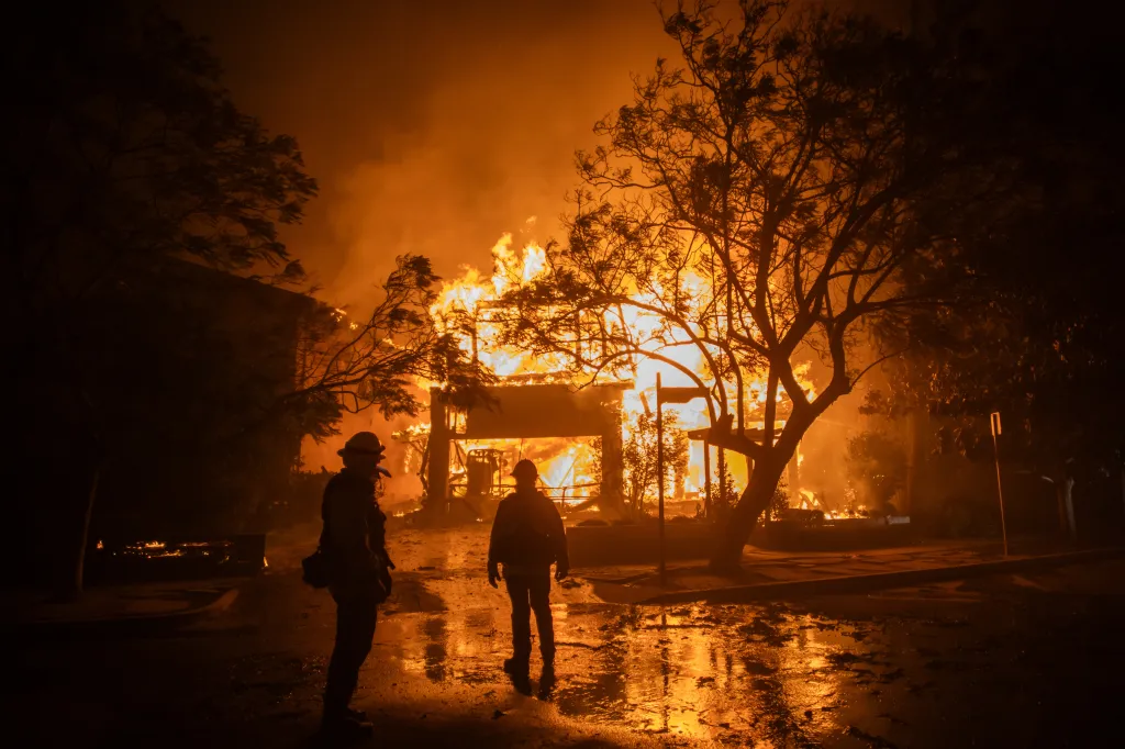 Firefighters watch a home burning during a wildfire in the Pacific Palisades neighborhood of Los Angeles.