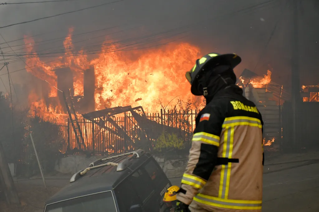 Firefighters try to extinguish a burning house during a wildfire in Concepcion, Chile,