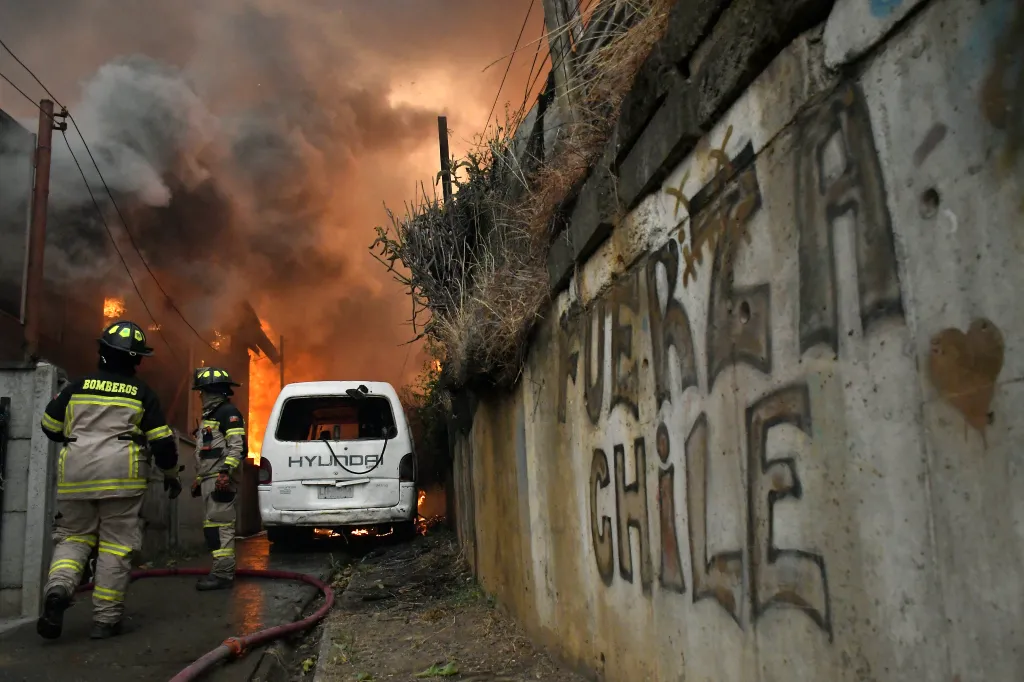 Firefighters try to extinguish a burning house during a wildfire in Concepcion, Chile, on January 18, 2026.