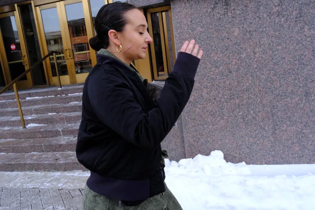 Natalie Greene attempts to shield her cut-up face with her hands while walking briskly into the courthouse.