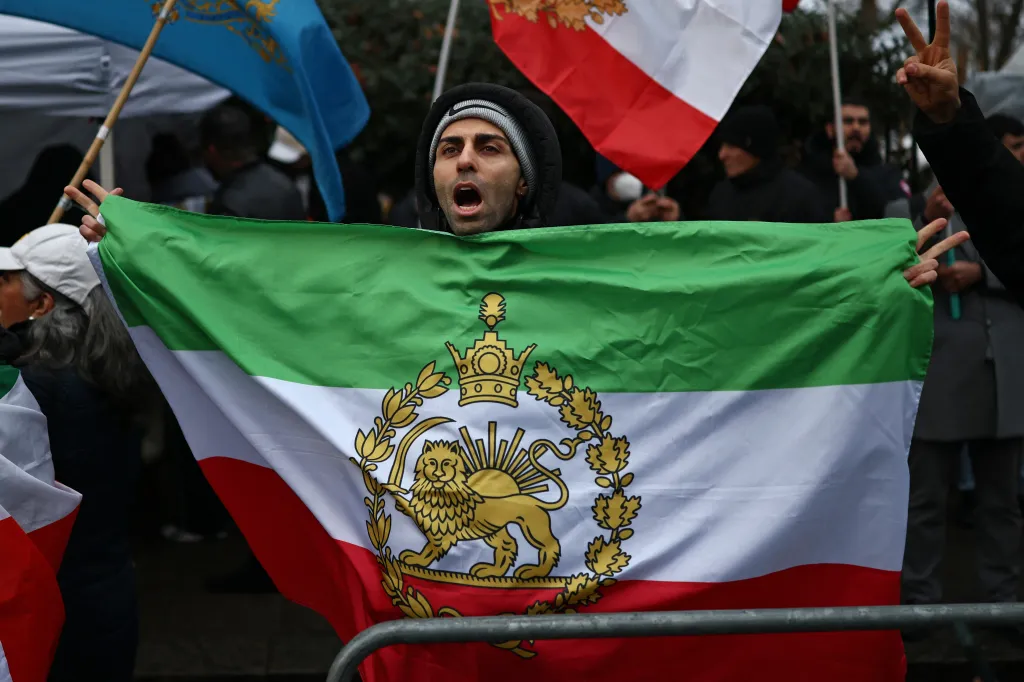 A protester holding the Iranian flag before the 1979 revolution, with the Lion and Sun emblems, at a gathering outside the Iranian Embassy in London.