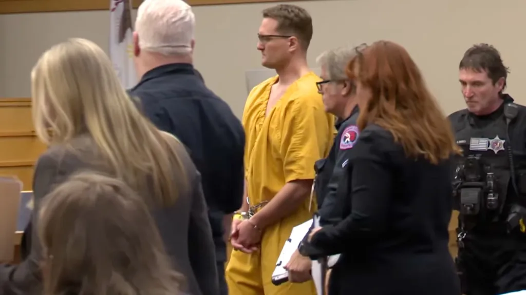 Michael David McKee in an orange jumpsuit and handcuffs in court.