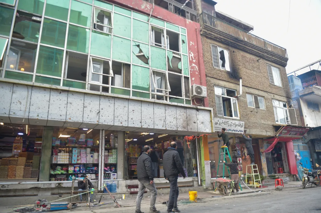 Locals walk past a building with shattered glass following an explosion in Kabul.