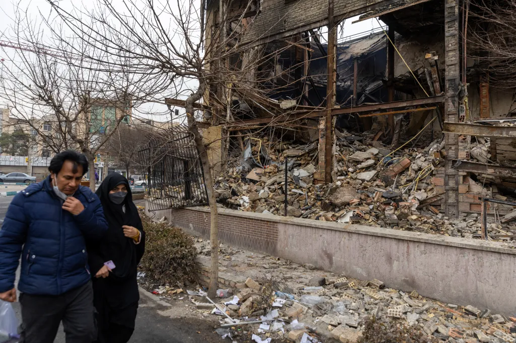 Iranians walking by a building destroyed during the ongoing protests over economic conditions in the country on Jan. 10, 2026.