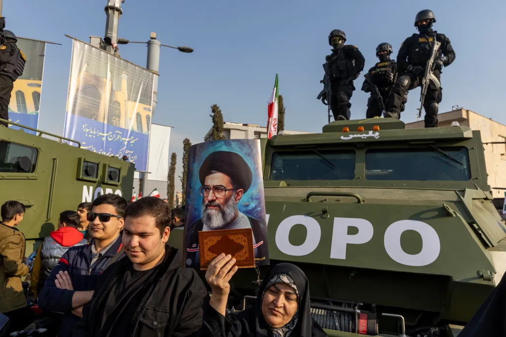 People attend a pro-government rally in Tehran, Iran, with security forces on an armored vehicle and a woman holding a portrait of Iranian leader Ali Khamenei.
