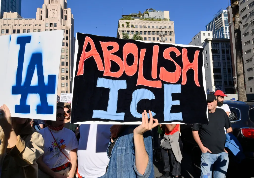 People protesting in Los Angeles, one holding a sign that says 