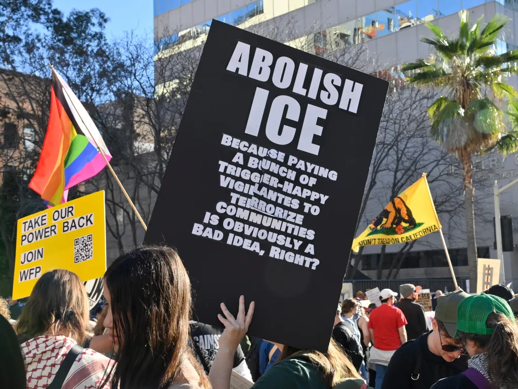 A protester holding a large black sign that reads 