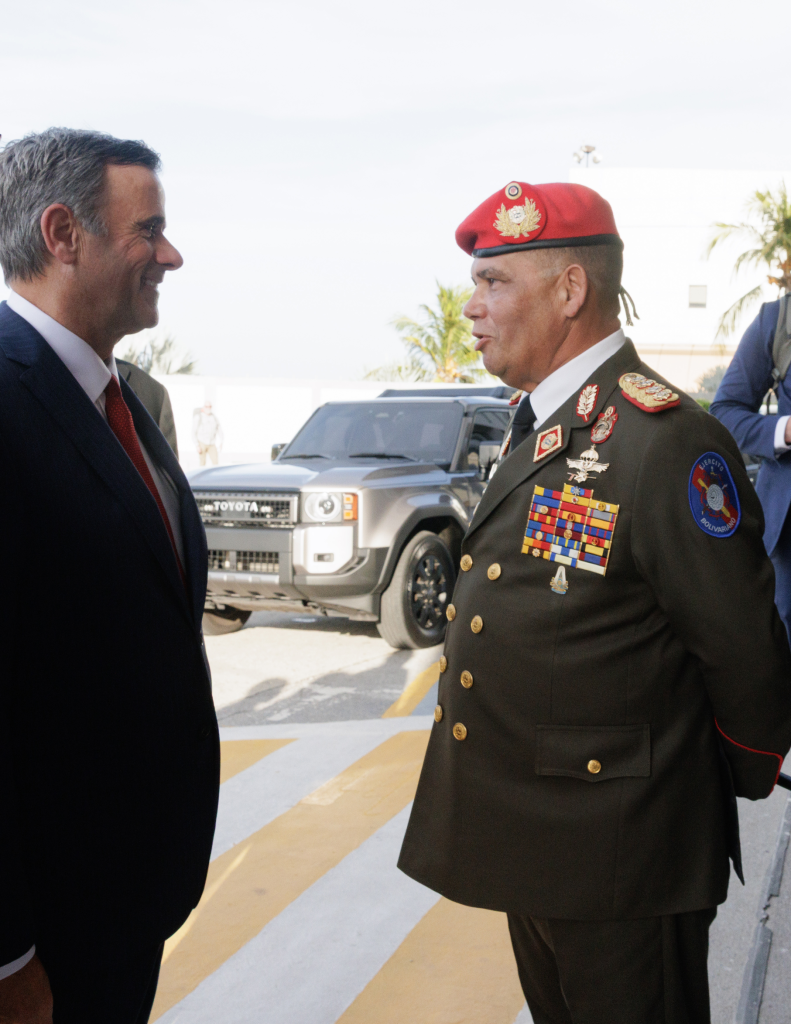 Two men talking; one in a suit and the other in a military uniform with a red beret.