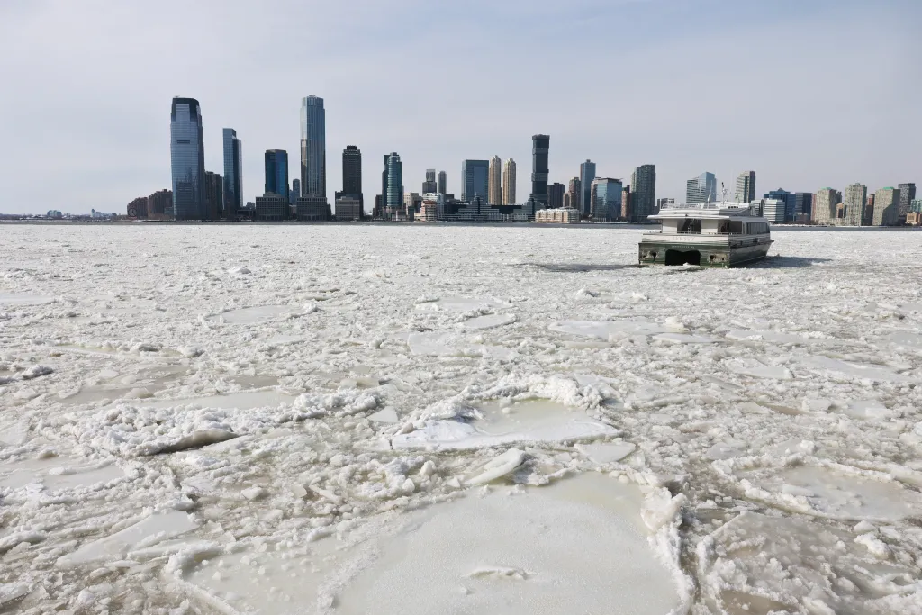 A ferry boat stuck in icy Hudson River with the New York skyline in the background.