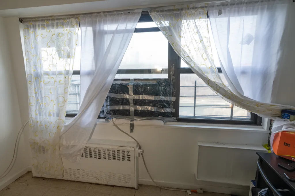 A window with an air conditioner wrapped in plastic and tape to prevent leaks.