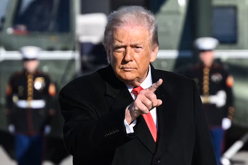 US President Donald Trump gestures as he walks to board Air Force One at Joint Base Andrews, Maryland on January 13, 2026.