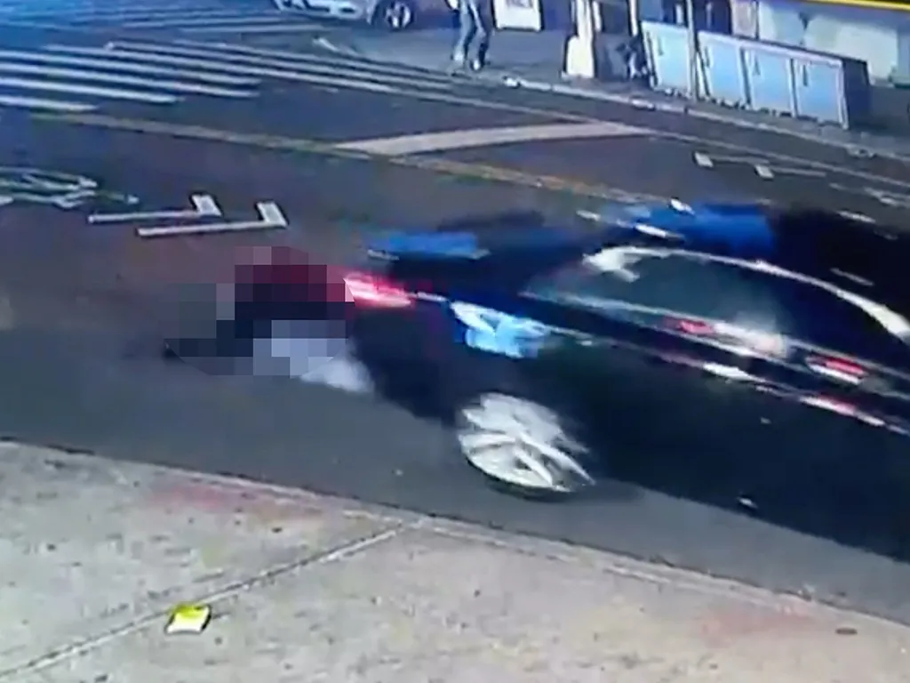 A blurred image from surveillance footage shows a person lying in the street as a car drives away.