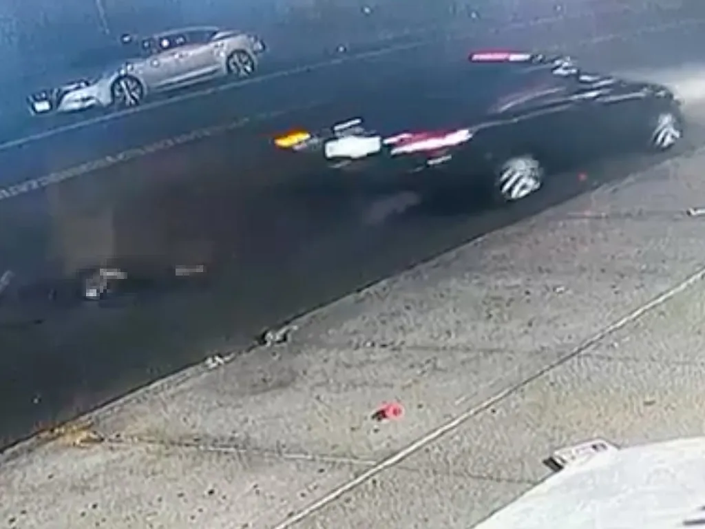 Surveillance video shows a person being dragged under a black vehicle on a street.