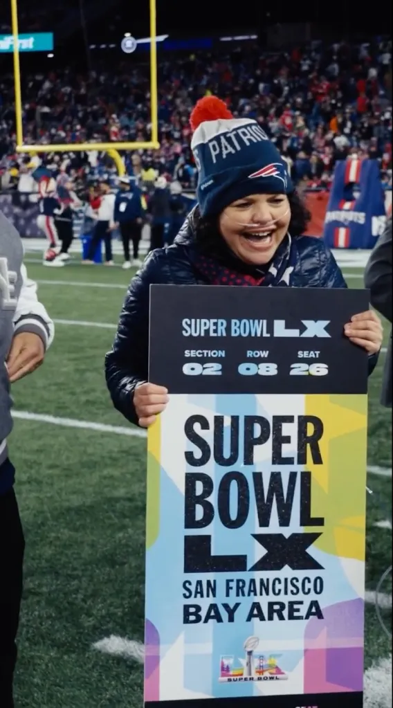 Shelly Sepulveda on a football field holding up a sign with her Super Bowl LX ticket information.