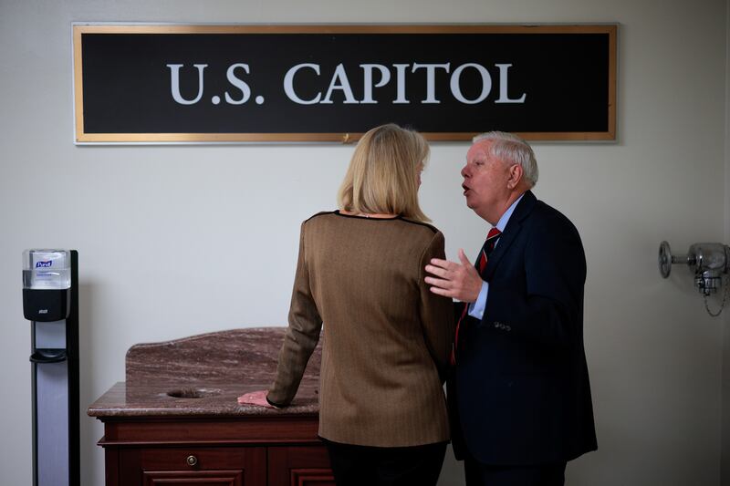 Sen. Lisa Murkowski (R-AK) (L) is pulled aside by Sen. Lindsey Graham (R-SC) in the basement of the U.S. Capitol before a vote on a Venezuela war powers resolution on January 14, 2026 in Washington, DC.