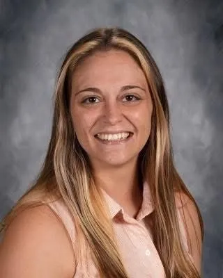Headshot of a smiling woman with long blonde hair and a light pink shirt.