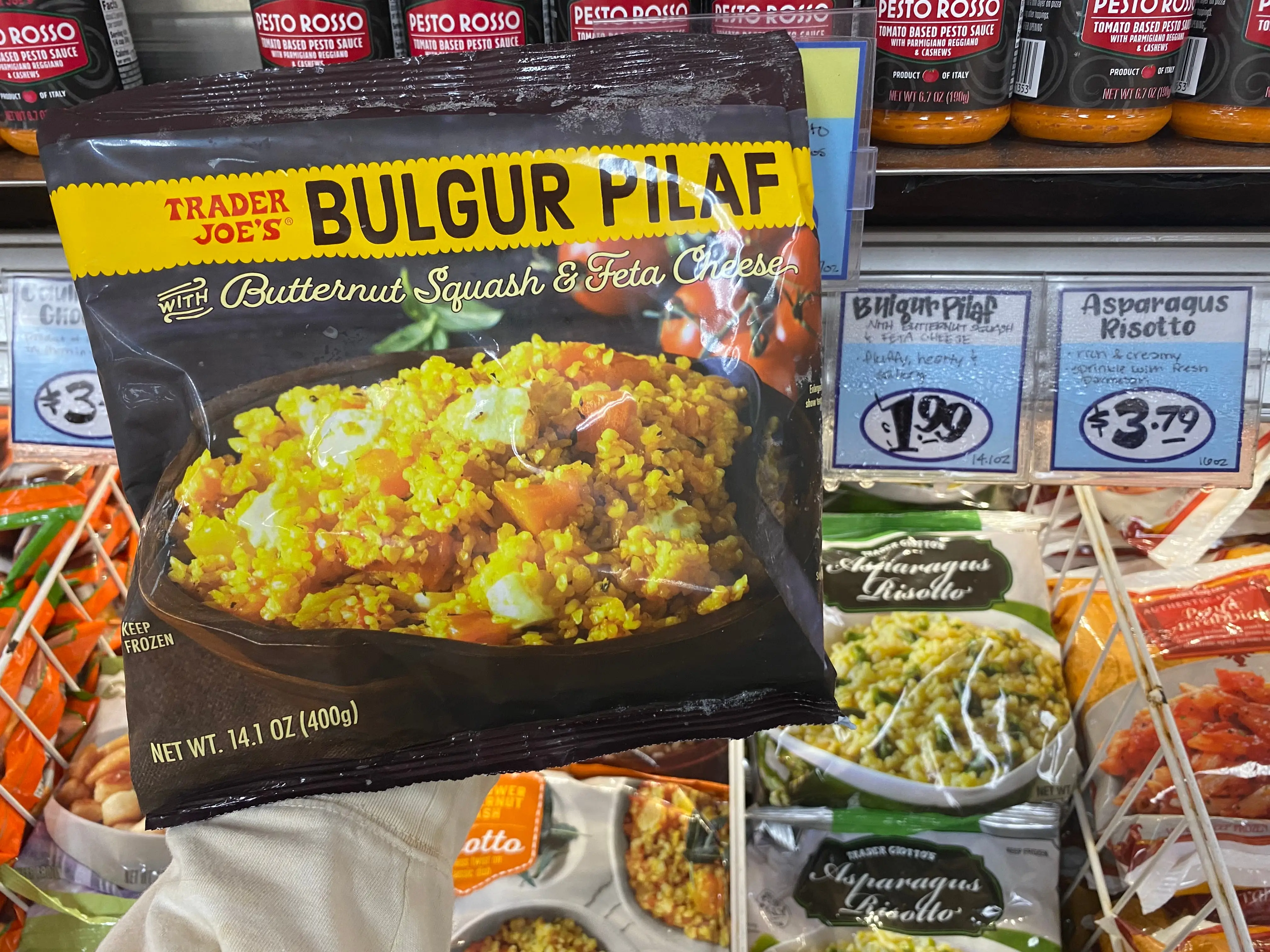 hand holding a bag of bulgar pilaf in the freezer aisle at trader joes