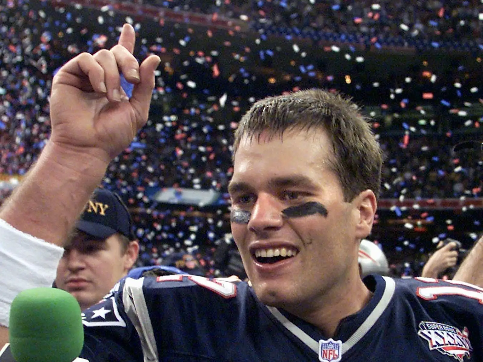 Tom Brady points up as he speaks to a reporter after winning Super Bowl XXXVI.