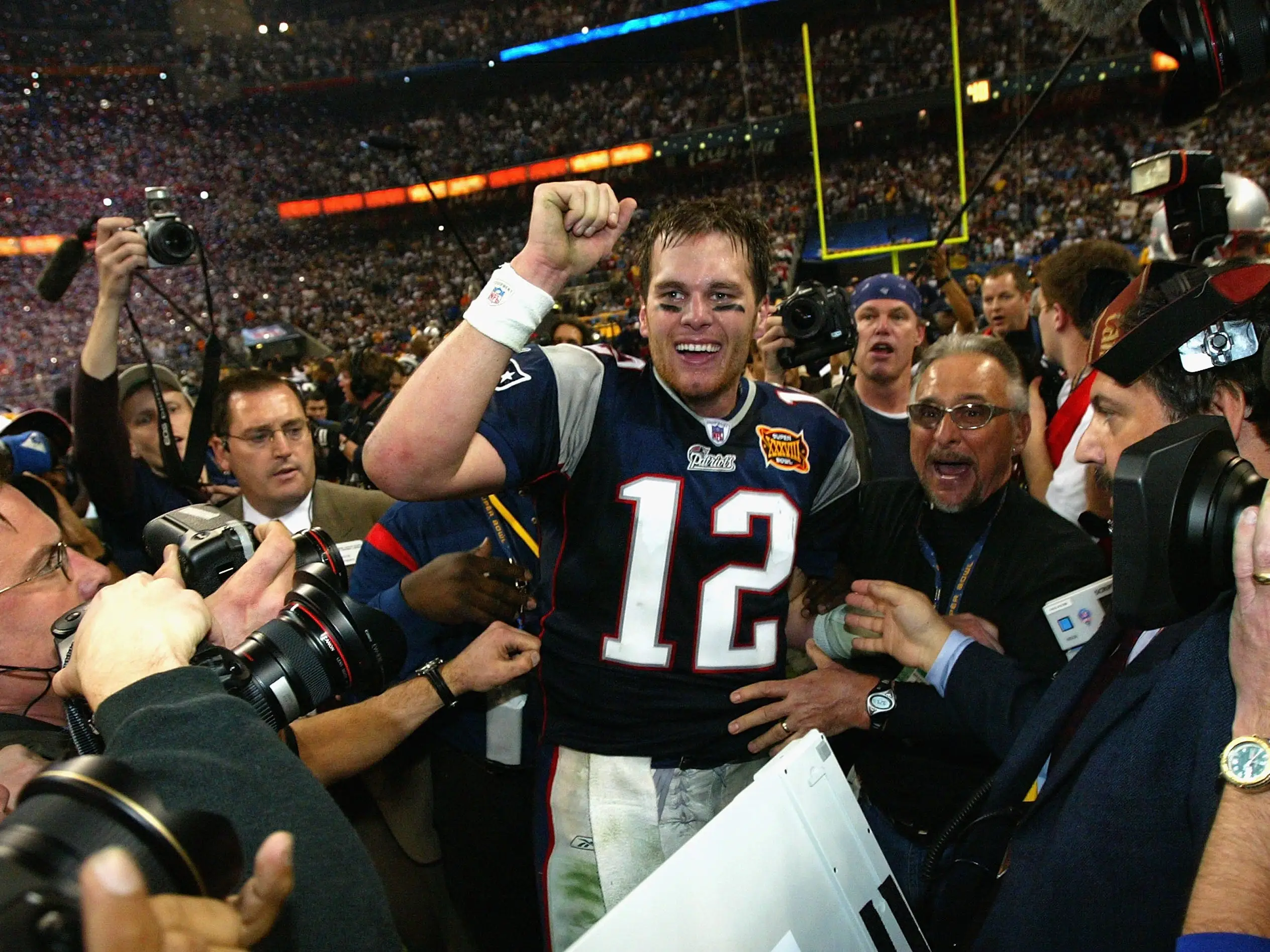 Tom Brady raises his fist as he's surrounded by reporters after winning Super Bowl XXXVIII.