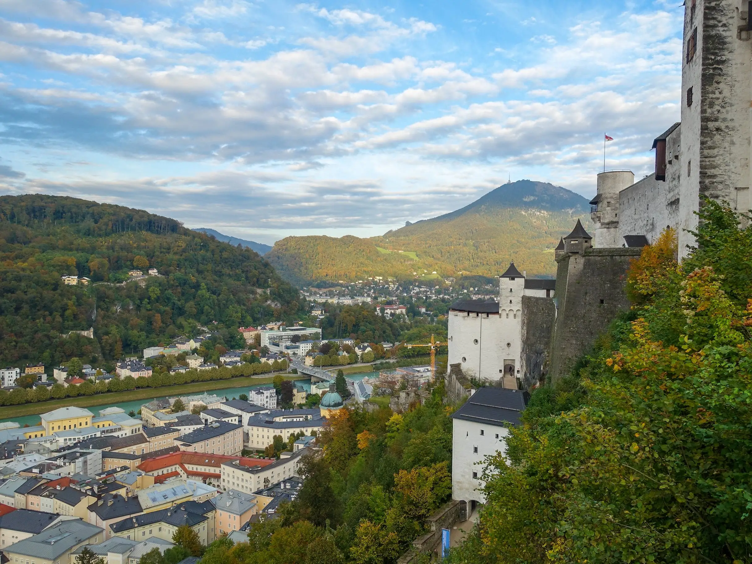 A view of the landscape in Salzburg with a castle and buildings in the foreground and mountains in the background