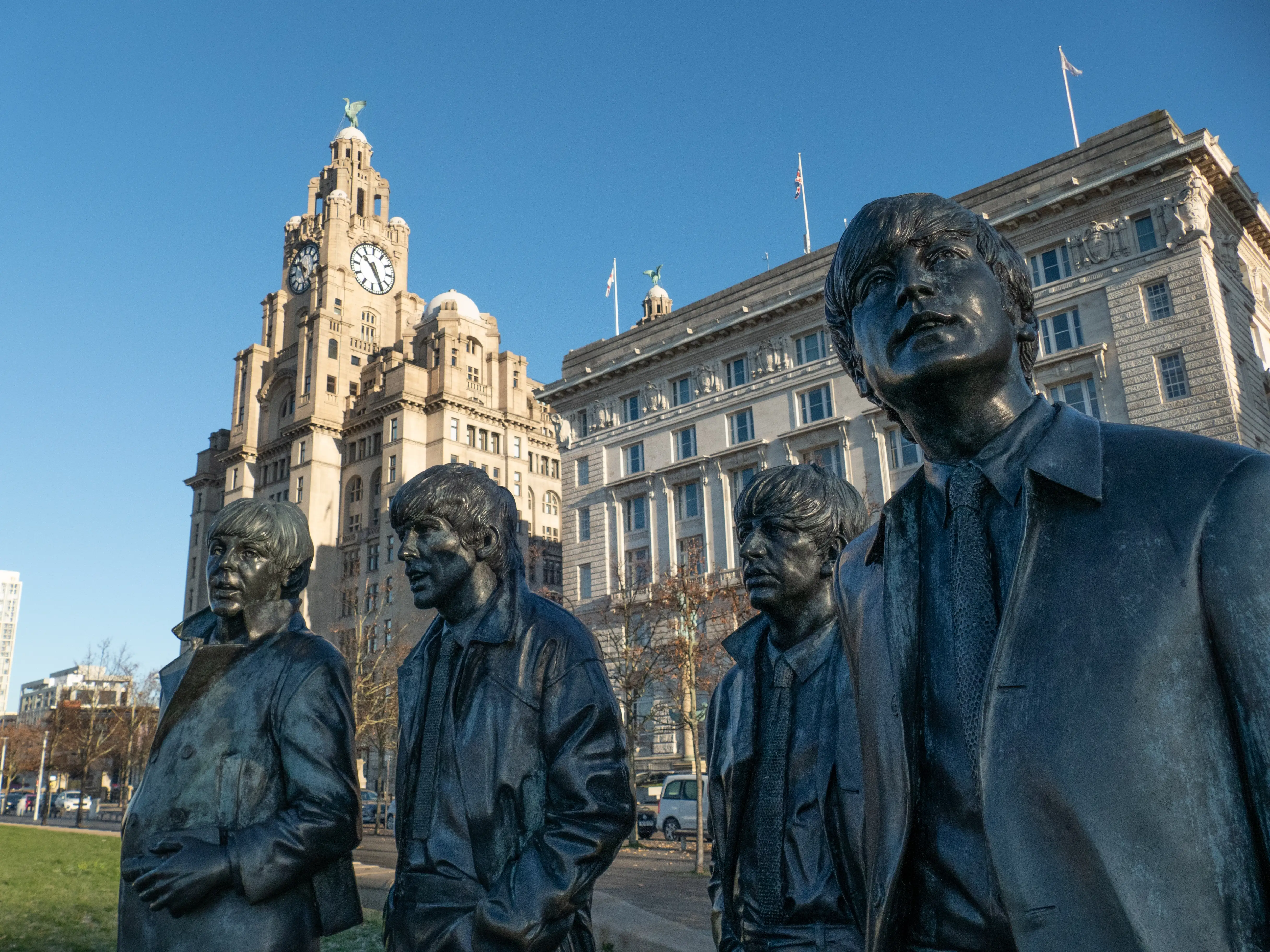 Statues of the Beatles in front of an ornate building.