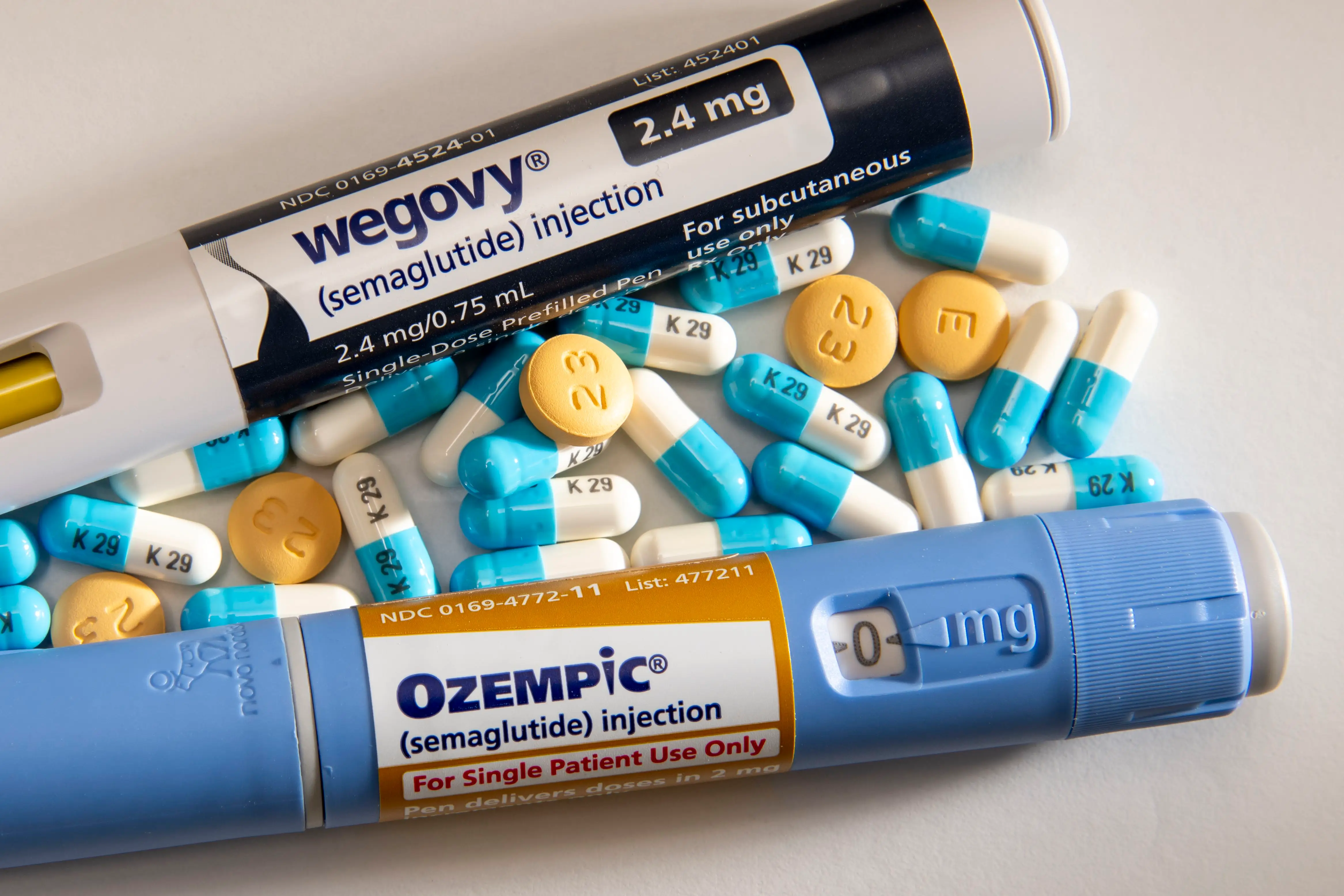 A close-up image of currently available injectable medications Wegovy and Ozempic along with pills for weight loss.