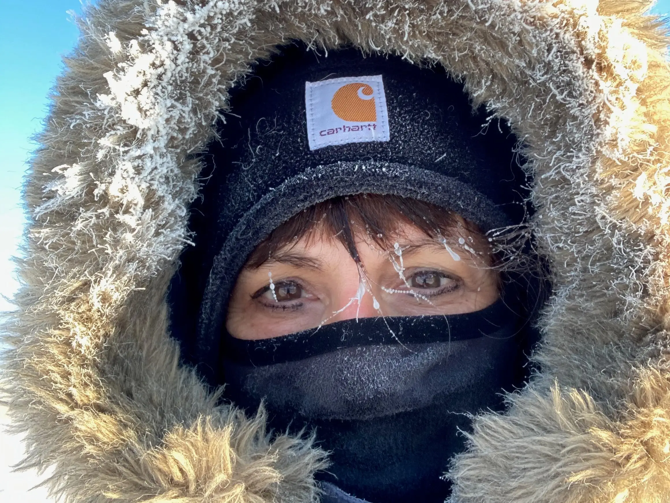 Amy wears a ski mask and a coat with a fur-lined hood, and pieces of her hair are frozen.