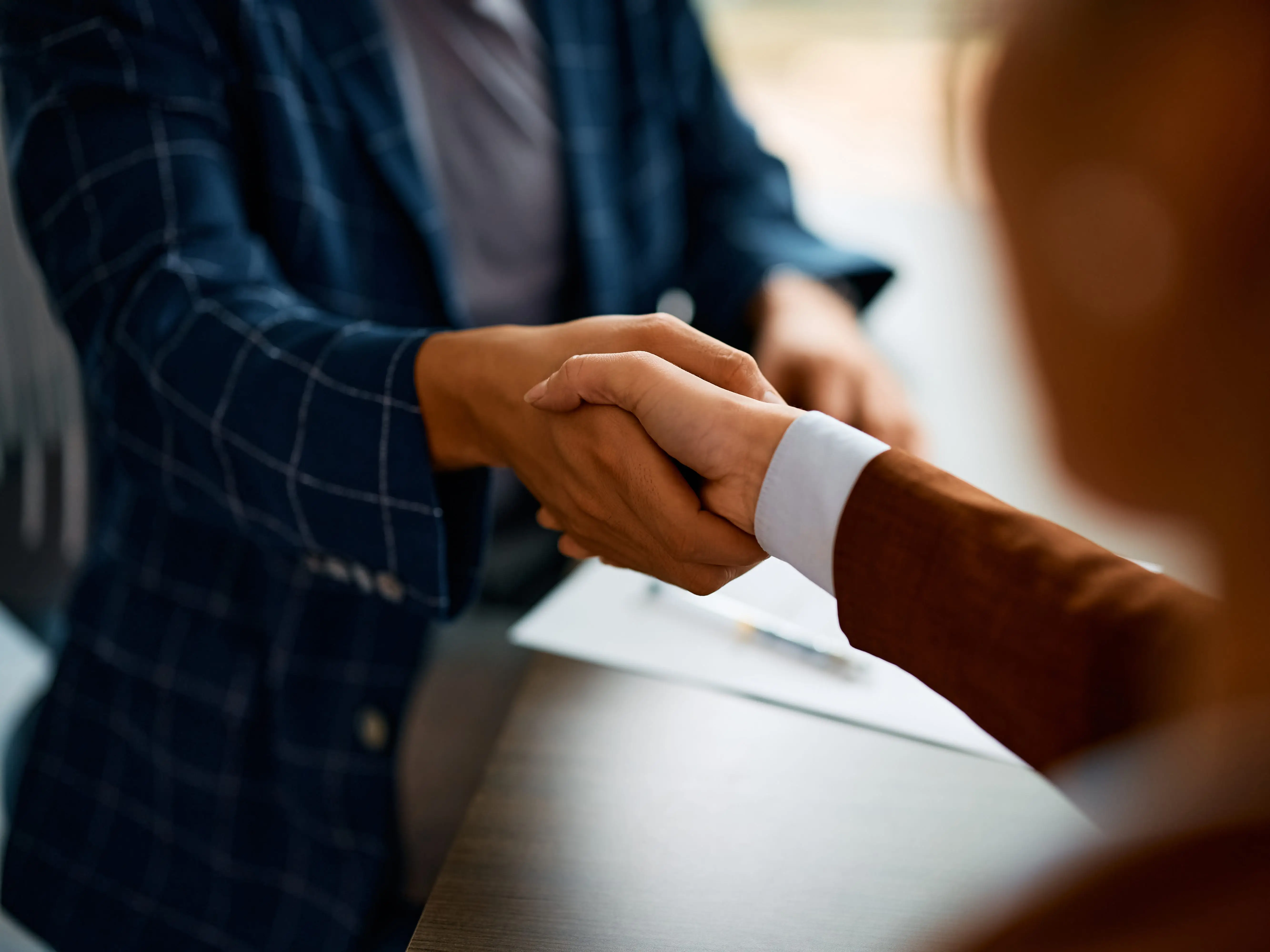 Someone in a blue blazer shaking someone's hand in a brown blazer.