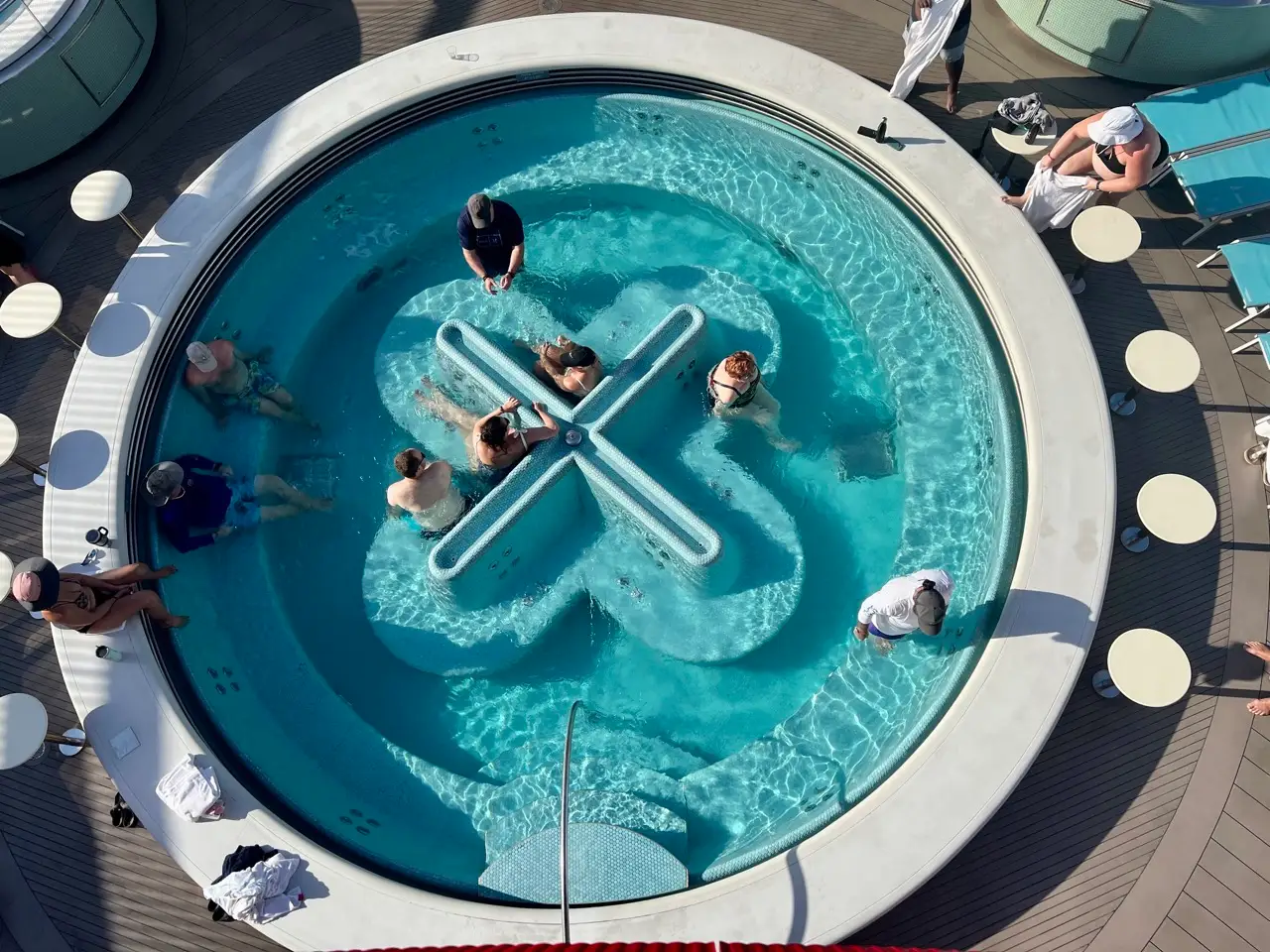 An overhead view of people in a circular pool on a cruise ship.