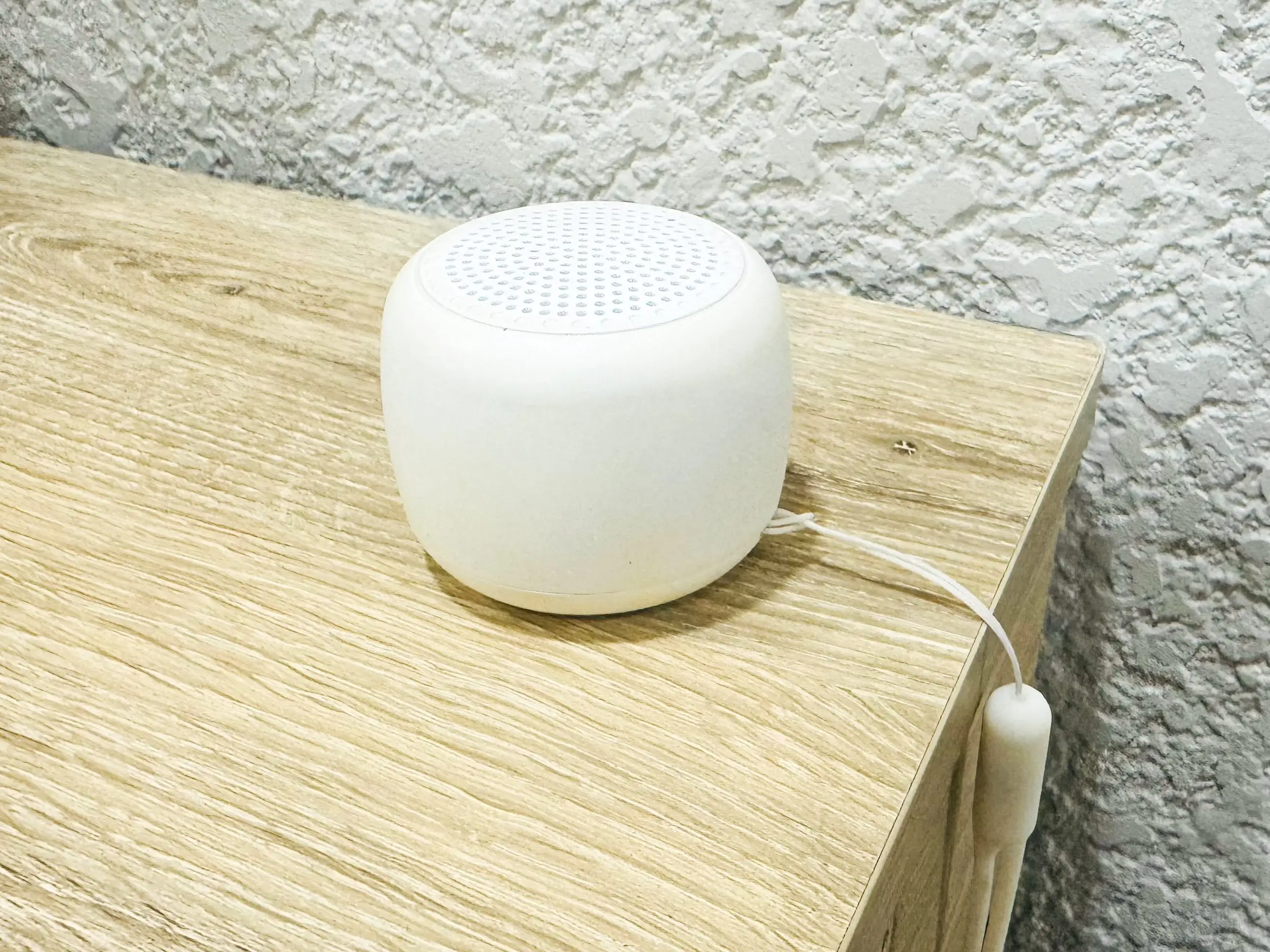 A portable white-noise machine on a wooden table.