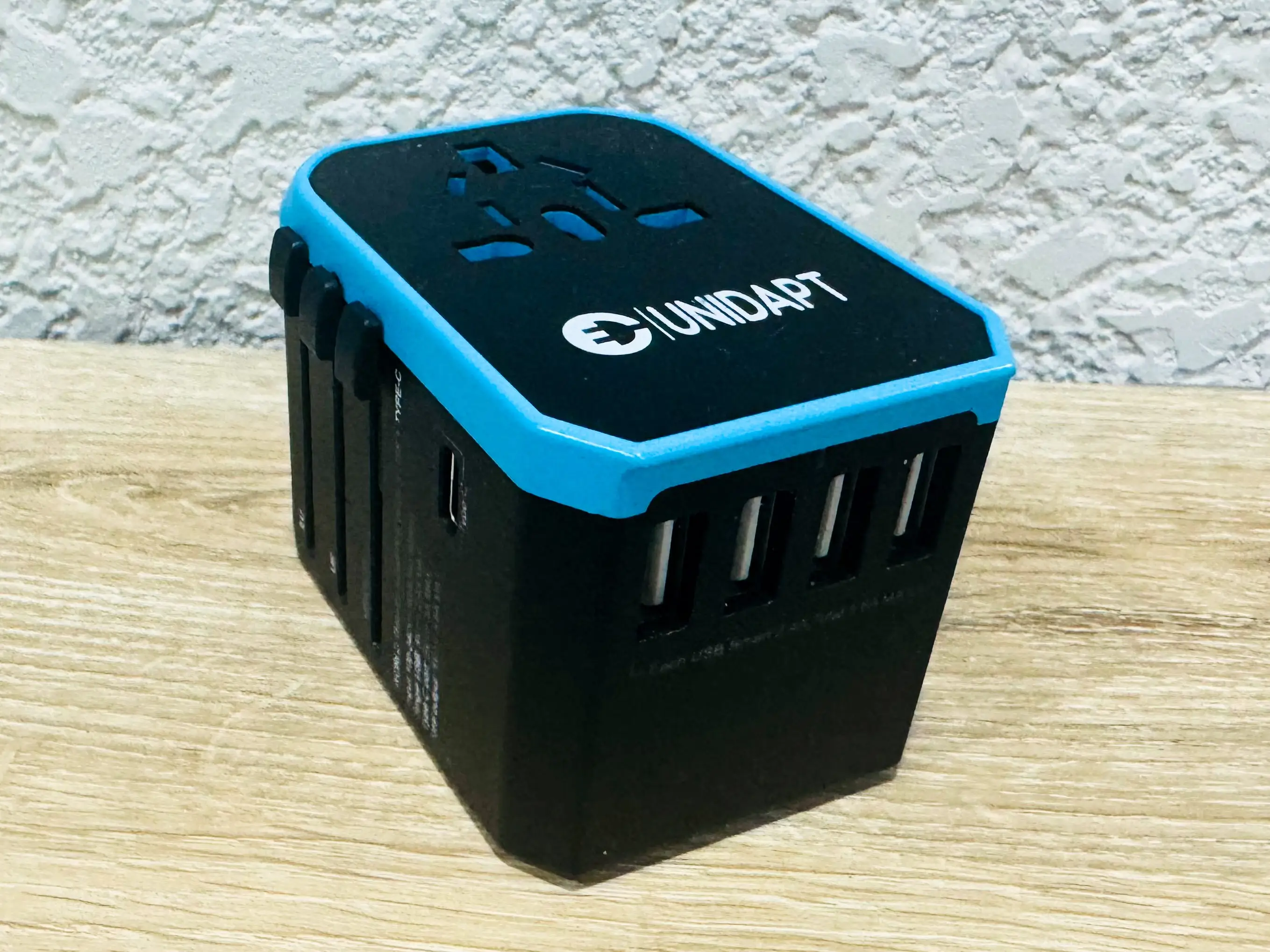 A blue-and-back outlet-converter box on a wooden table.