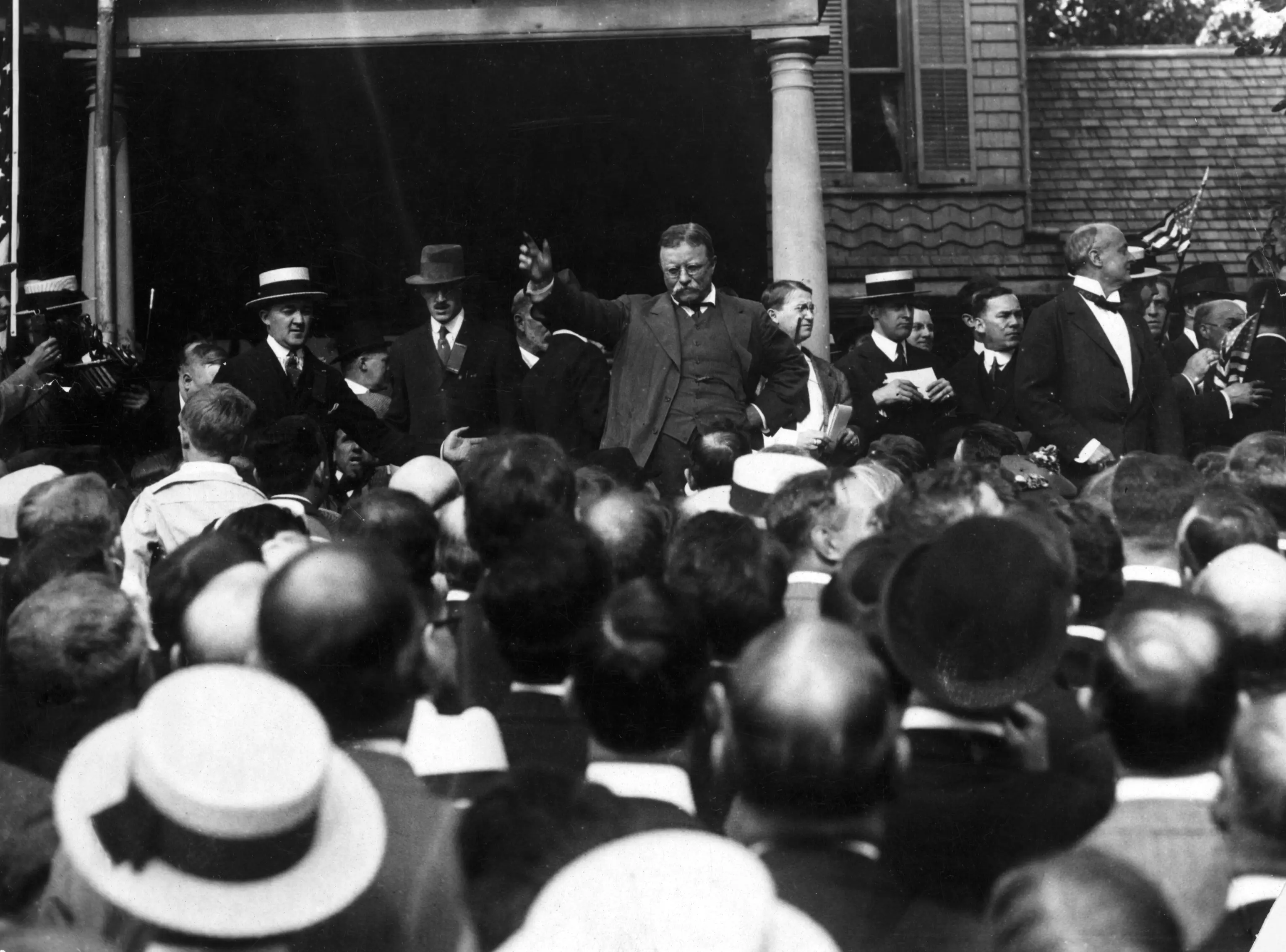 United States President Theodore Roosevelt gestures to make a point as he addresses a crowd from the steps of a building. View is from the crowd, overhead. Undated photograph, circa 1905.