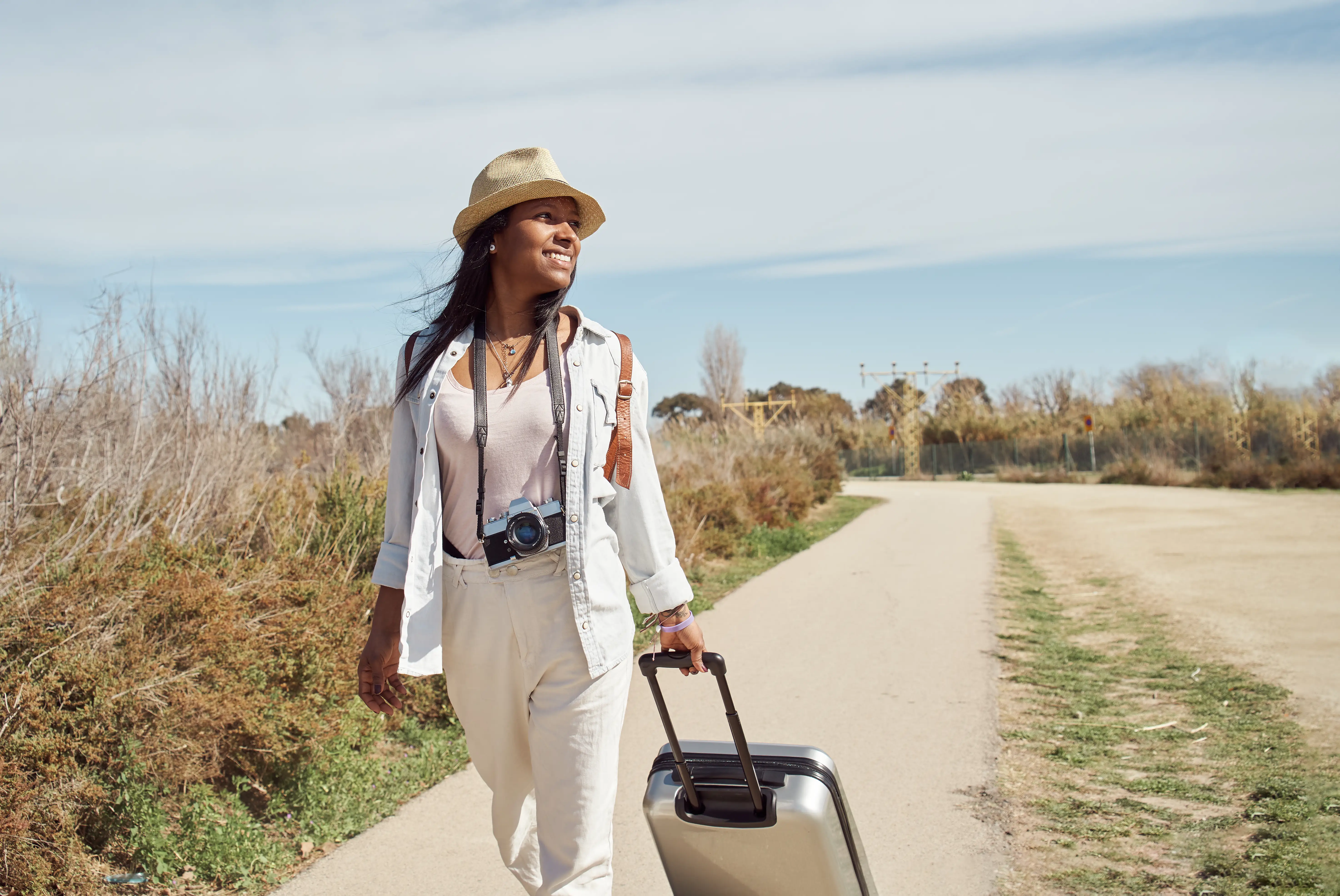 Woman with travel insurance walks along pathway with luggage