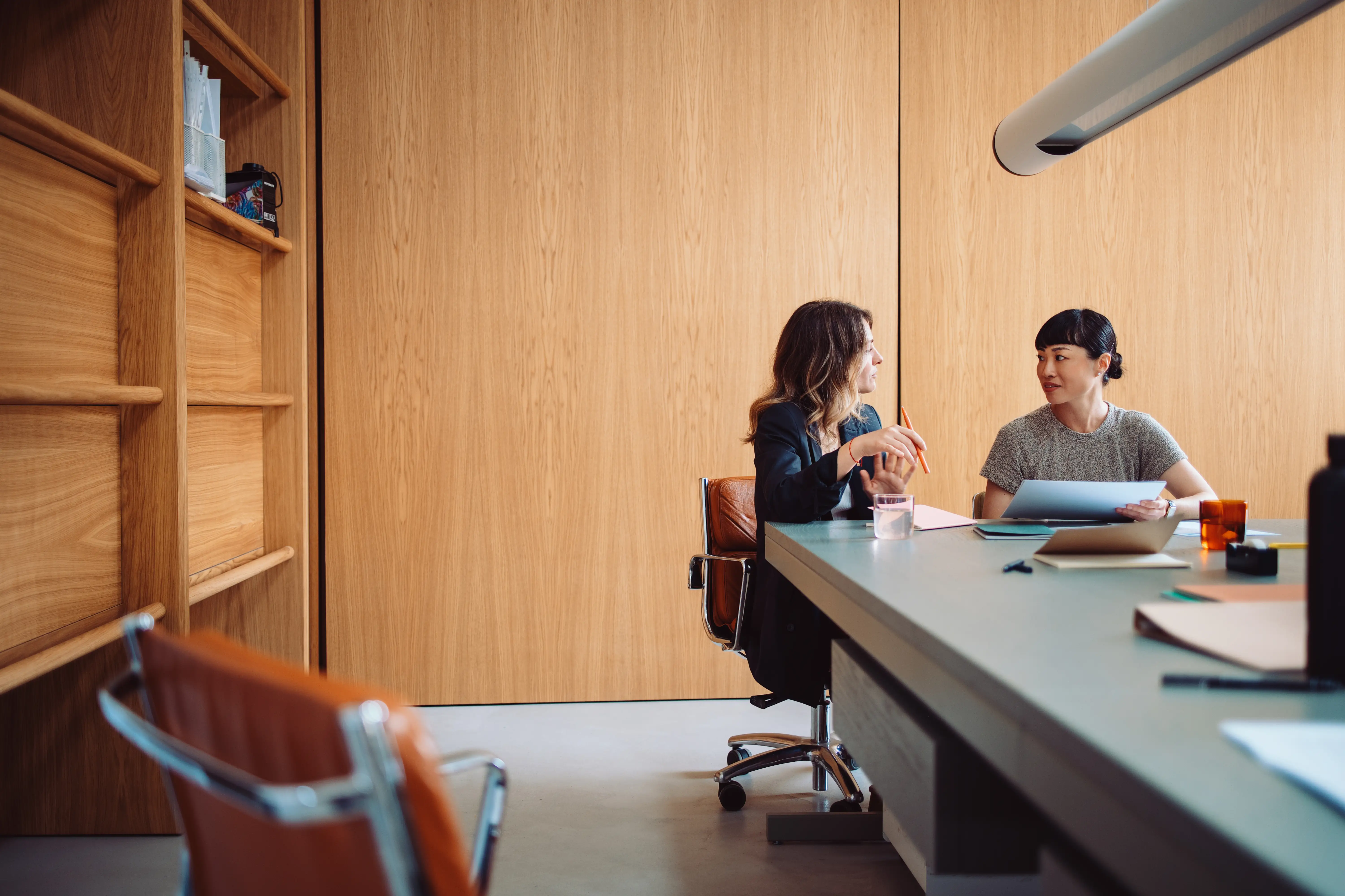 Two women sat on a table in a boardroom