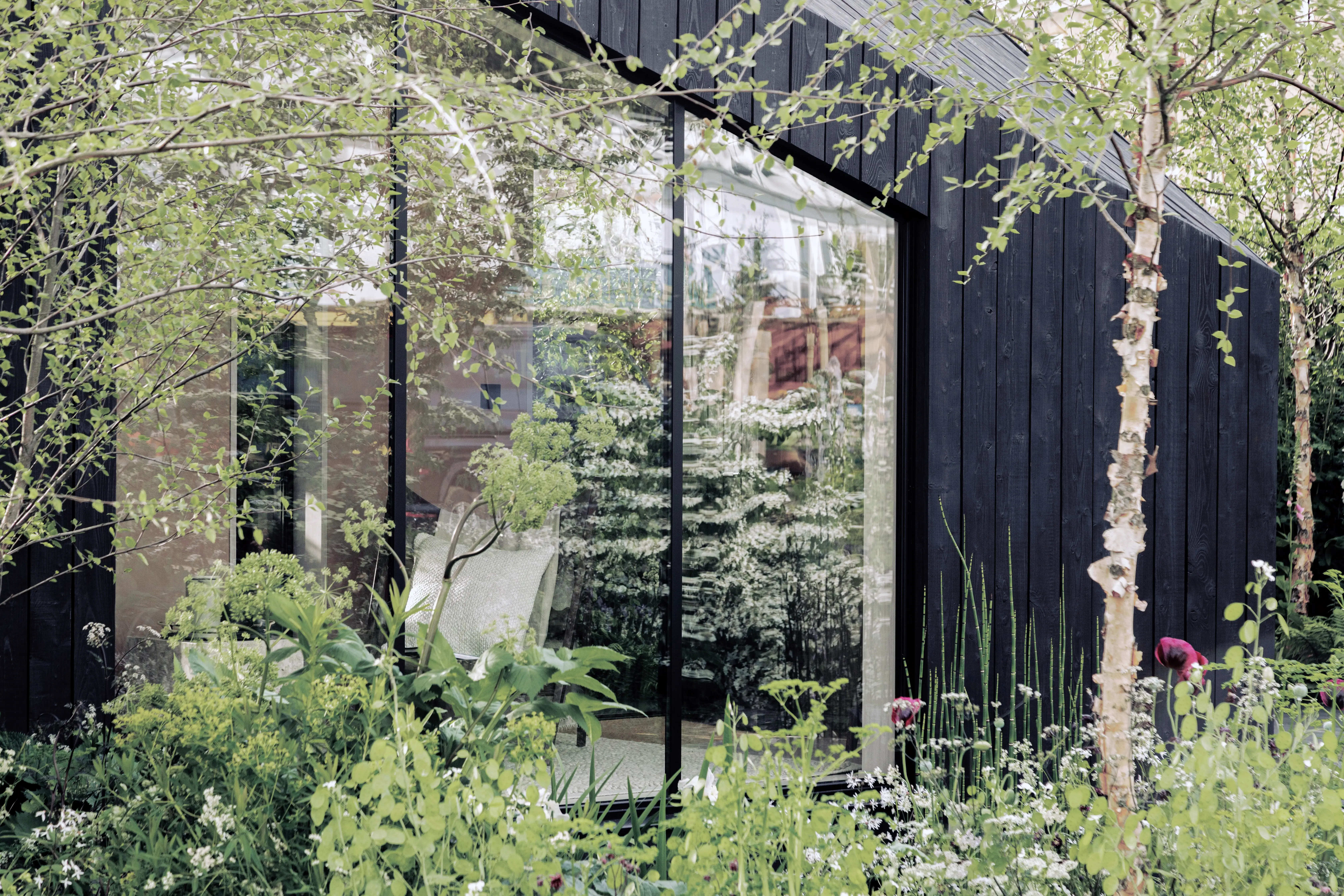 The exterior of a tiny Koto home surrounded by trees and flowers.