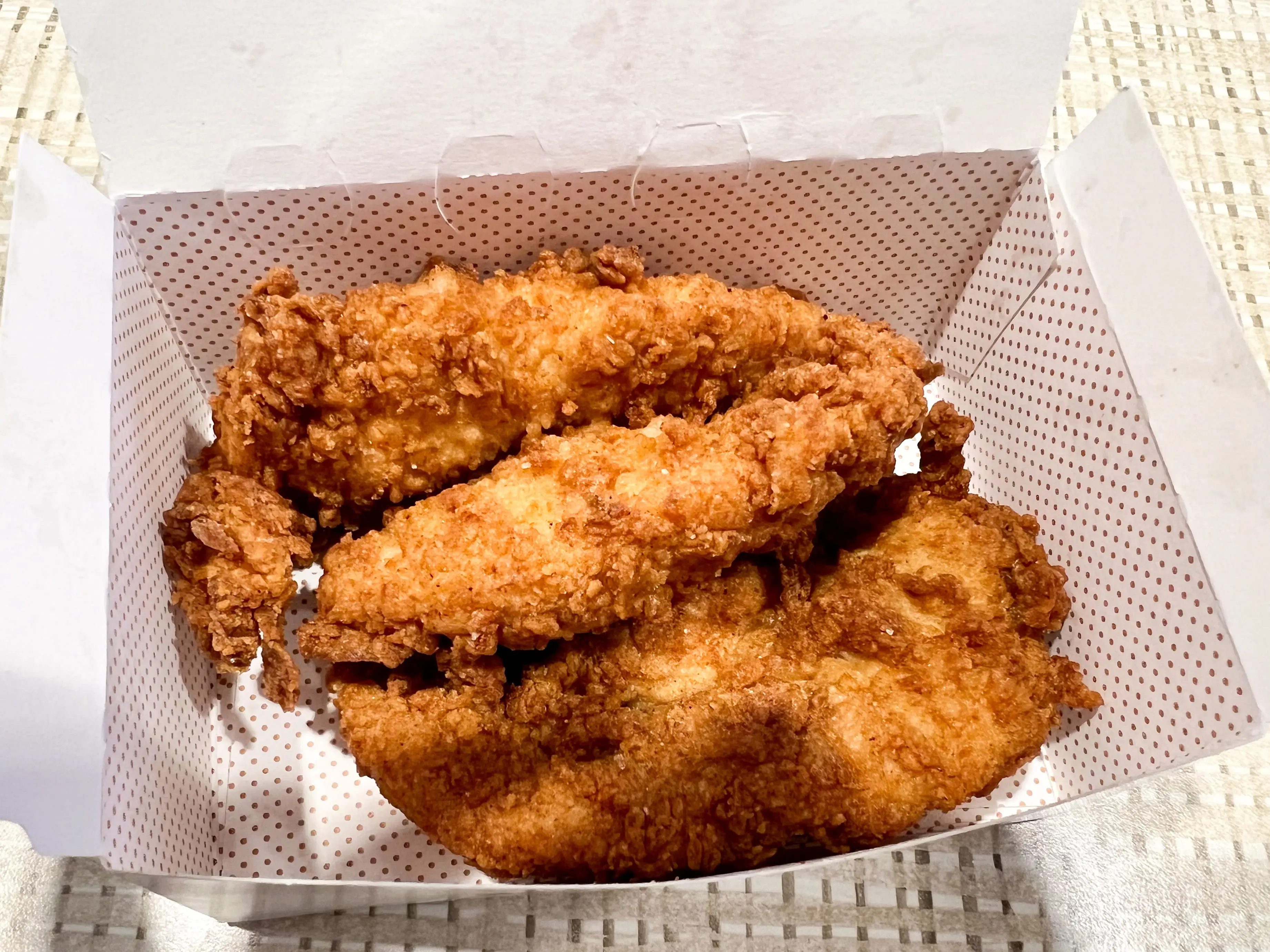 Three chicken tenders in a box.