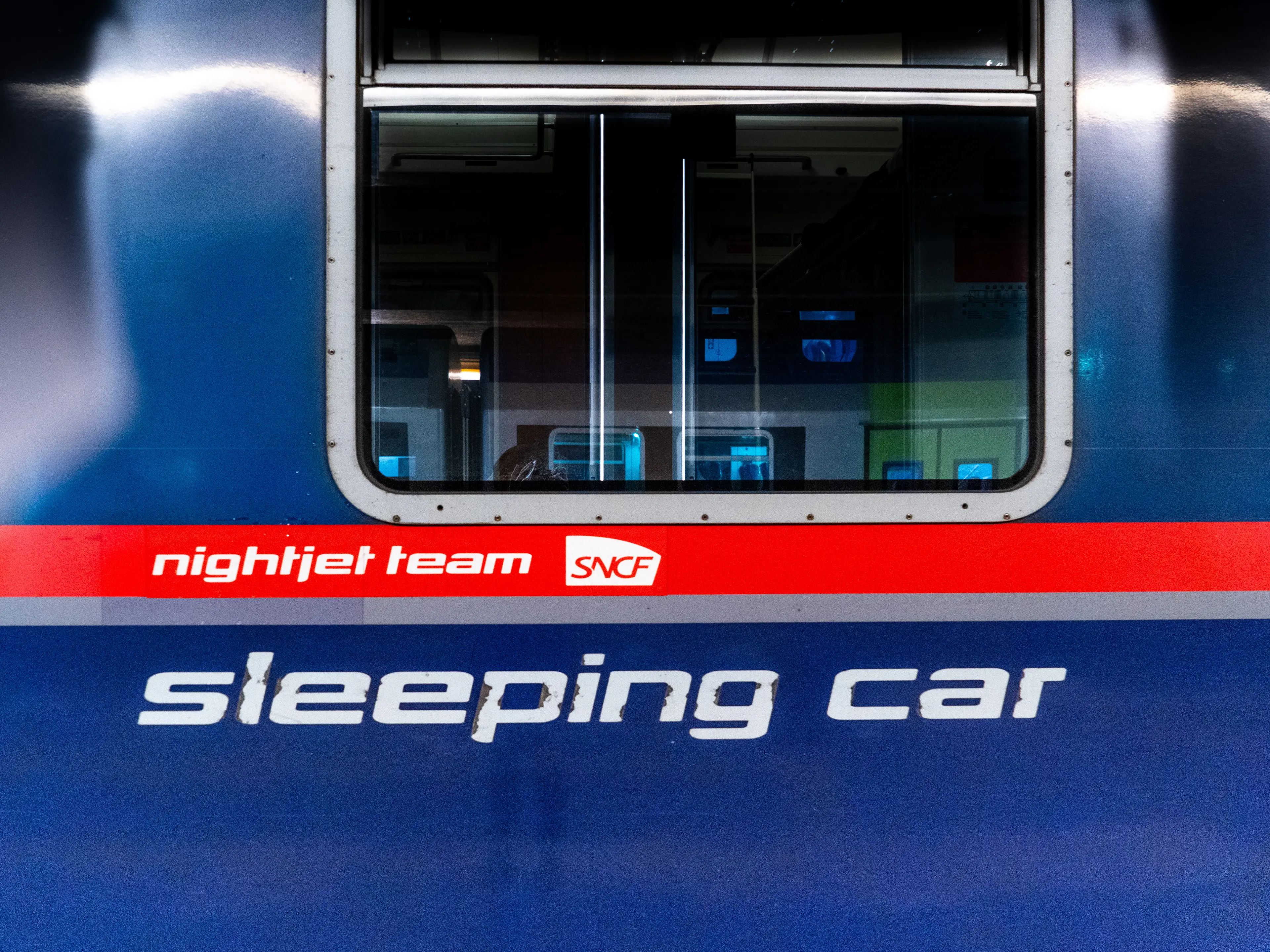 A close up of the exterior of a blue sleeping car on a train