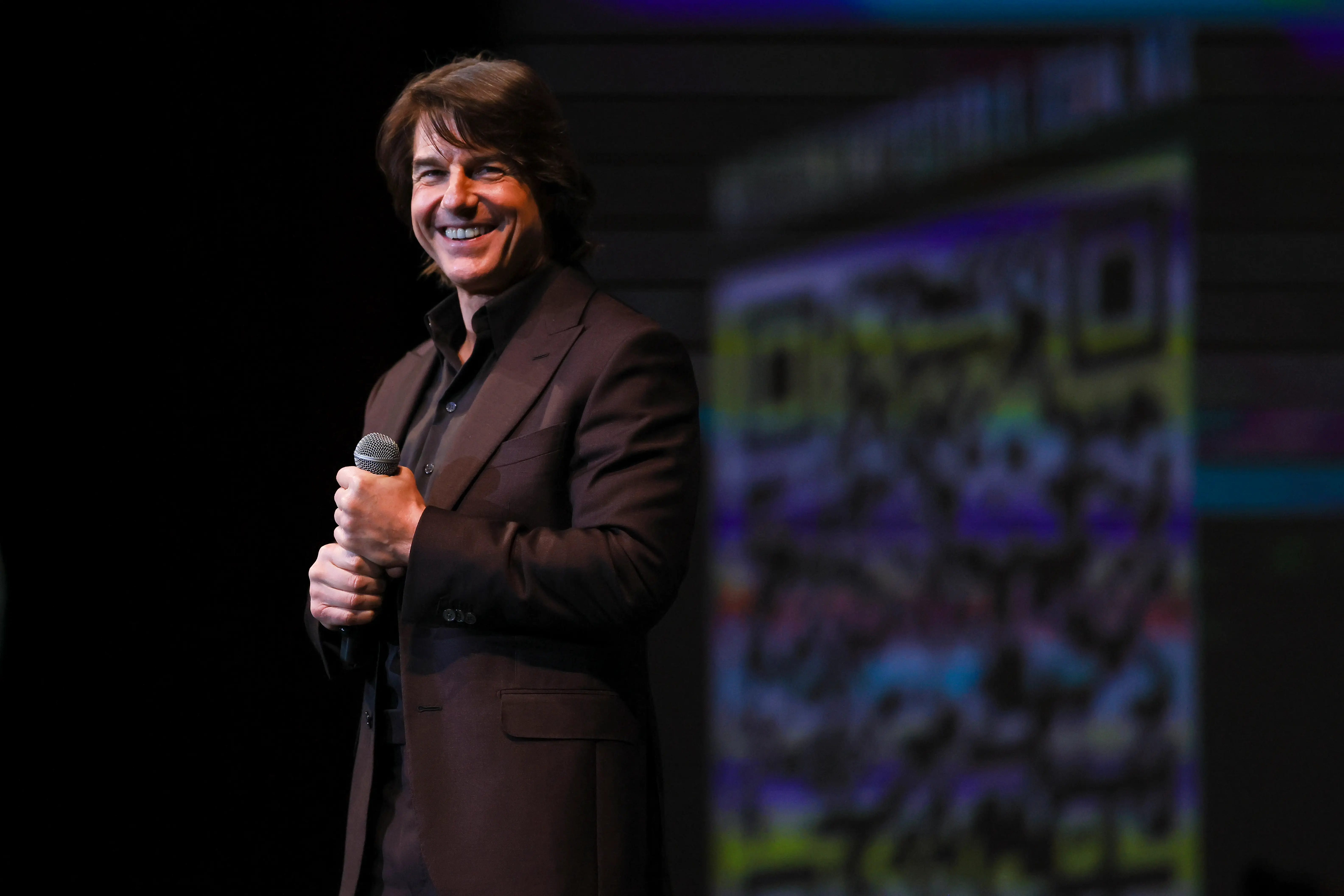 Tom Cruise in a suit holding a microphone