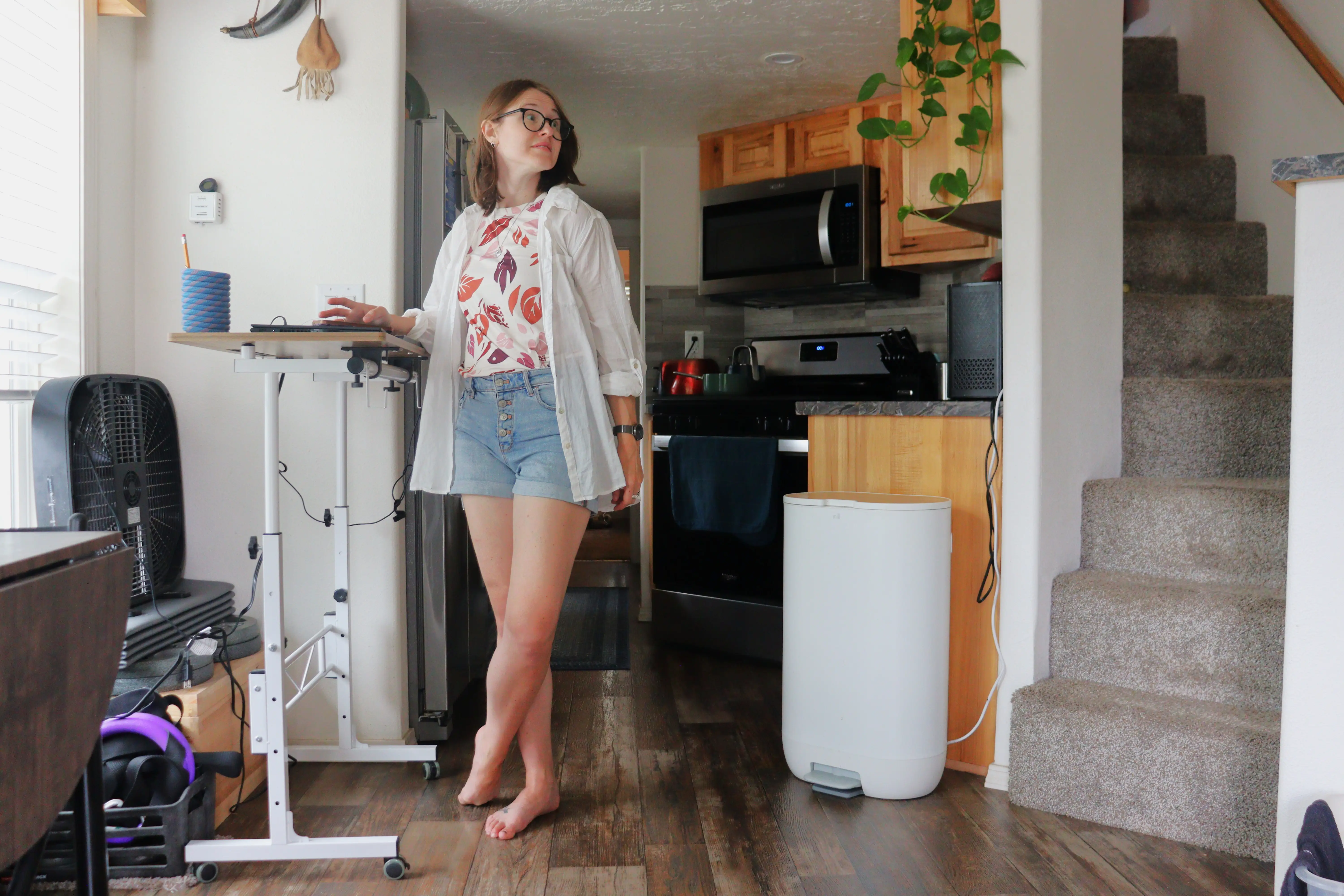 Author Amber McDaniel standing at raised standing desk in kitchen of tiny home